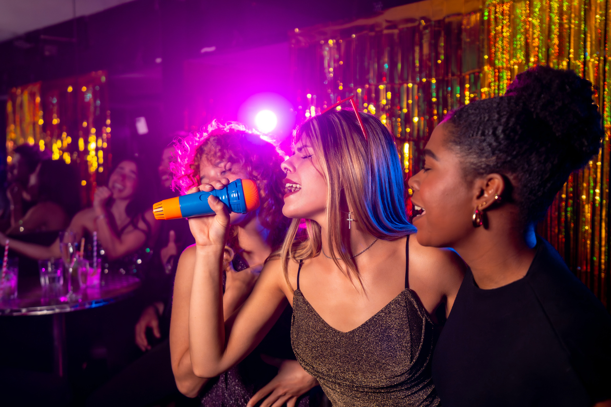 Young women singing karaoke in nightclub