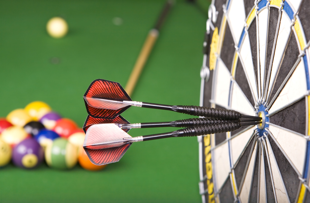 darts in a dart board with a pool game in the background