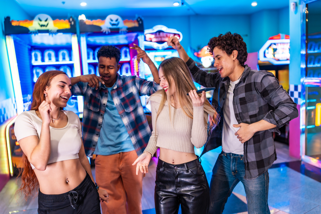 Young friends singing karaoke and having fun at the arcade