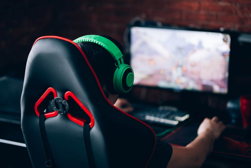 Computer games, playing place, young gamer plays computer games with headphones,