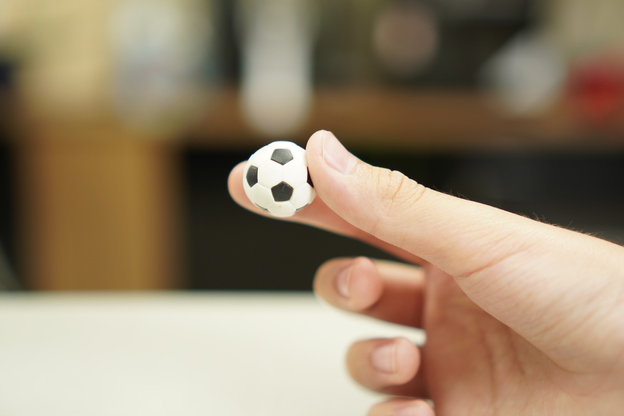 A hand holding a tiny foosball ball