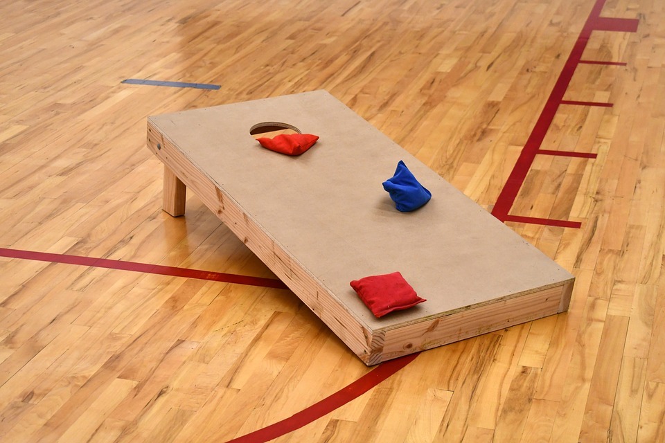 A cornhole board in the middle of a basketball court