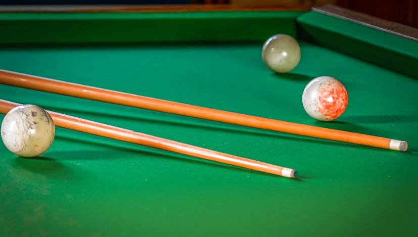 two one-piece pool cues on a pool table