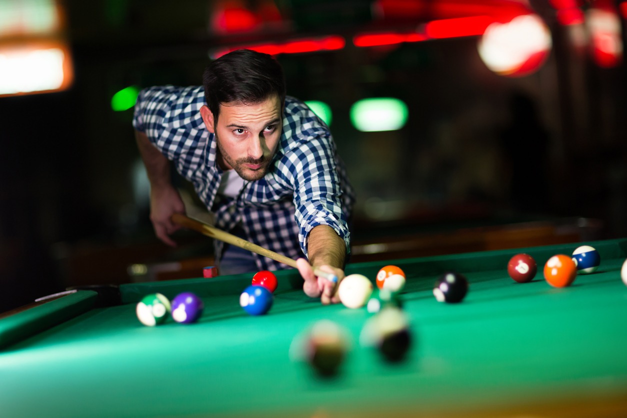 A player focusing on pocketing a shot at a pool table