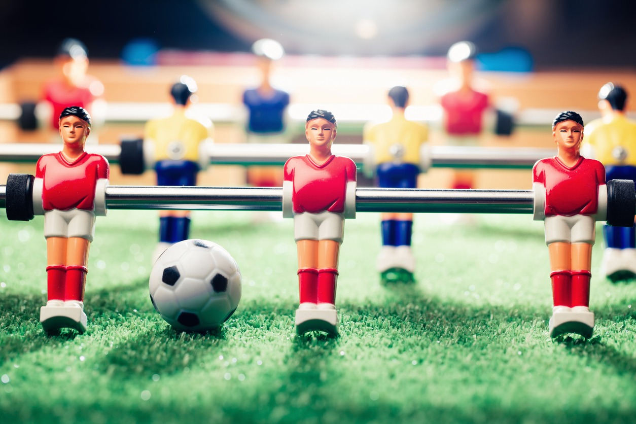 a close-up photo of a foosball table, players and ball
