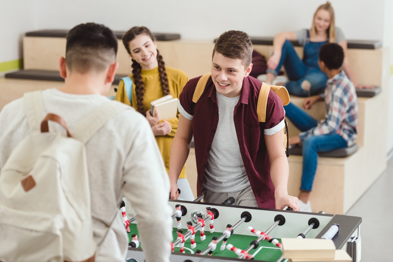high school students playing table football at school corridor